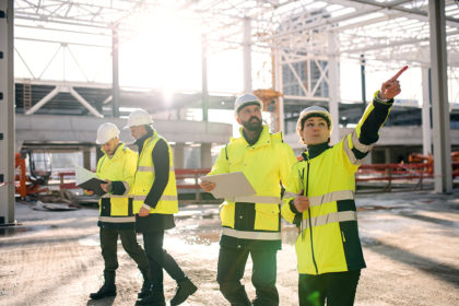 Group Of Engineers Standing Outdoors On Construction Site, Worki